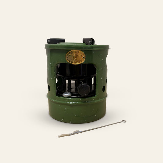 Groen geëmailleerd petroleumstel met zwarte brander, draaiknop en vuldop, met aansteekstaafje ervoor